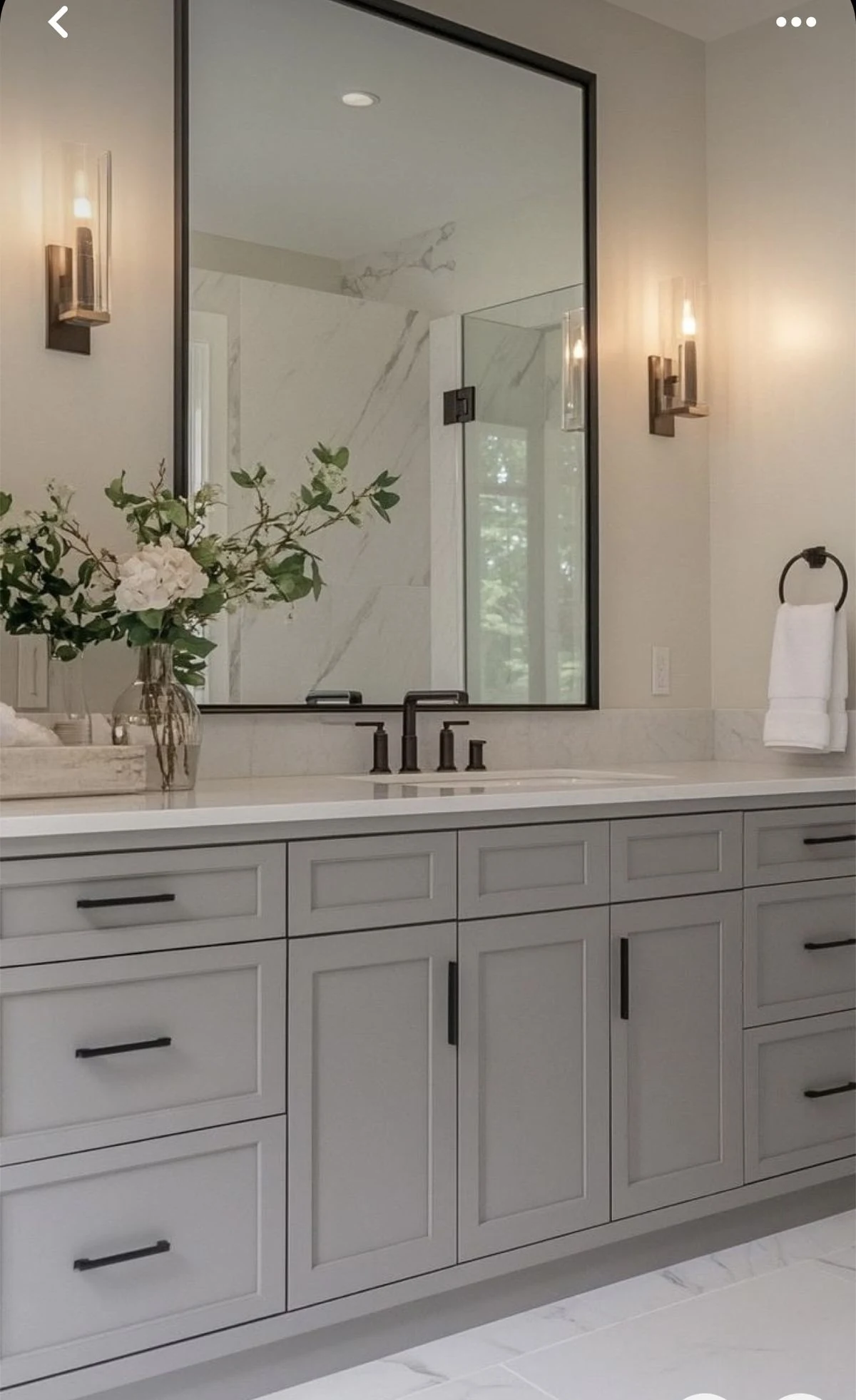 Bathroom vanity with grey shaker cabinets and black framed mirror