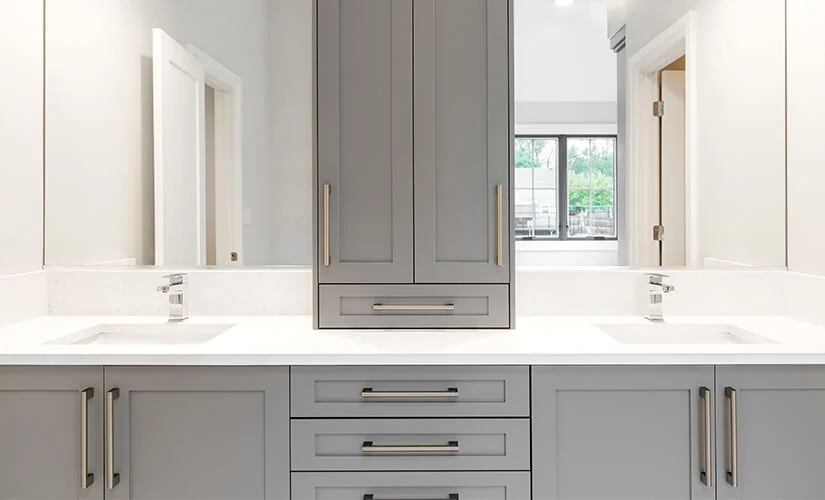 White bathroom cabinetry around window with quartz-look countertop