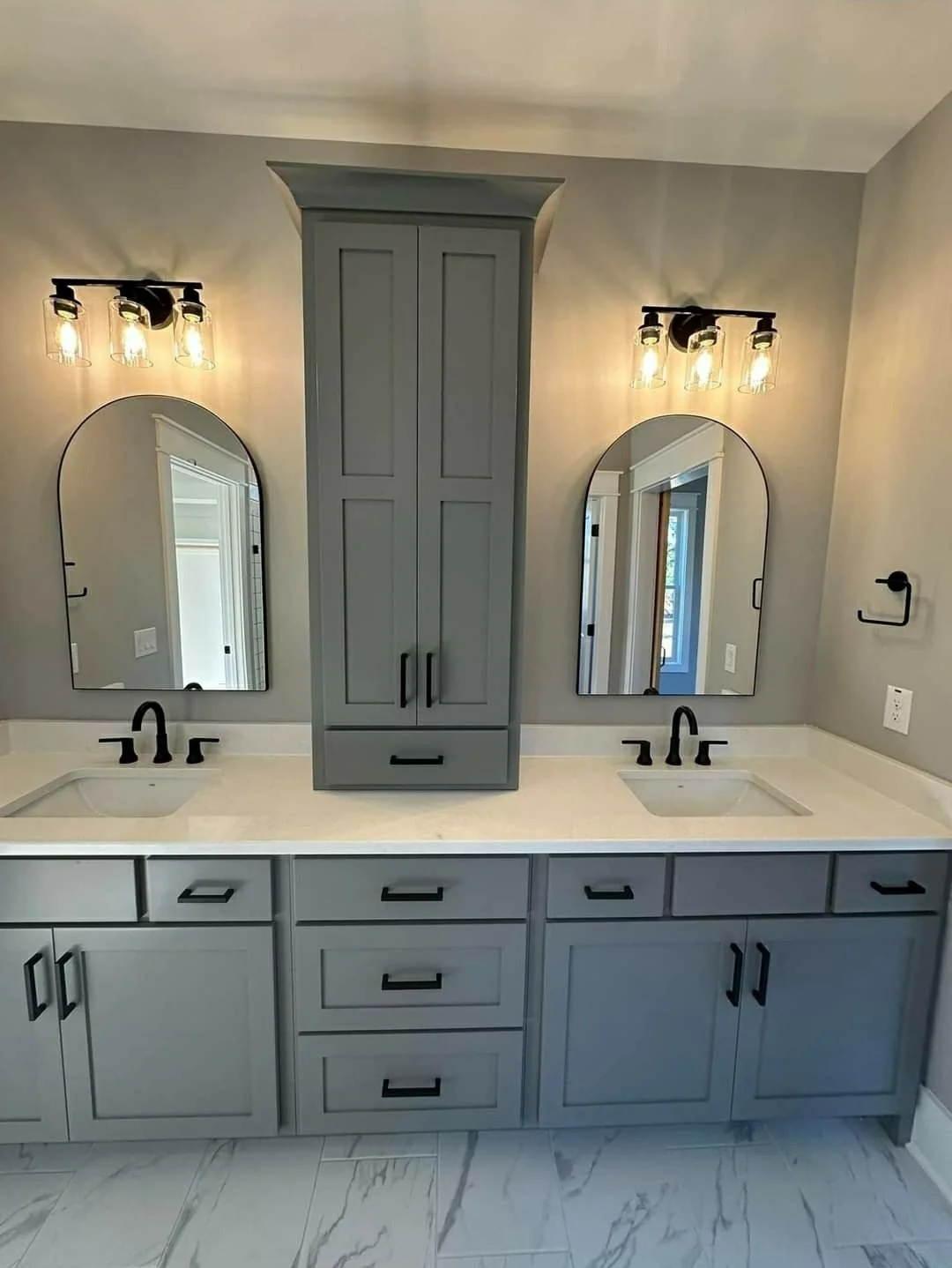 Dark bathroom vanity with rounded mirrors and brass lighting