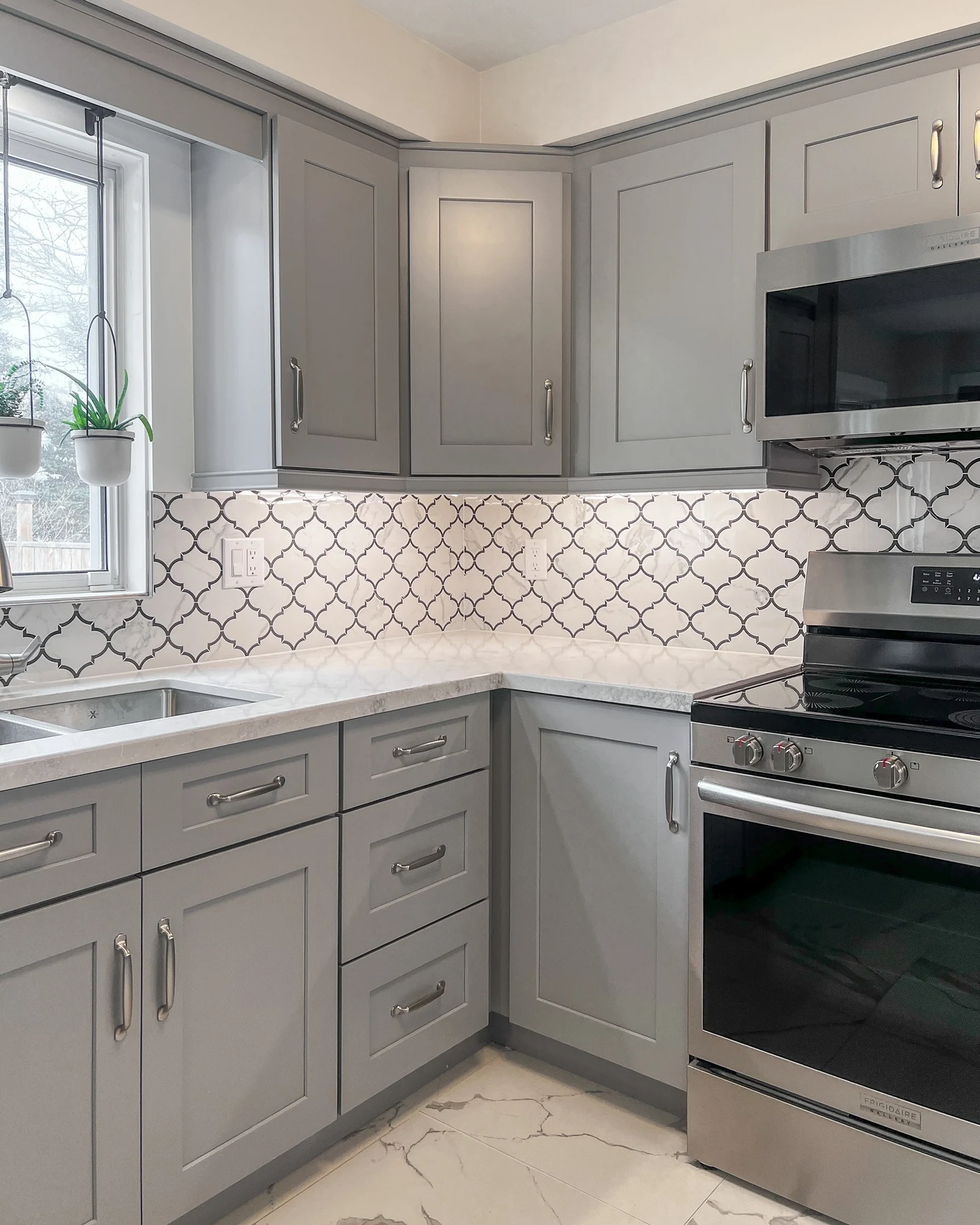 Kitchen with pale grey cabinets and patterned stone countertops