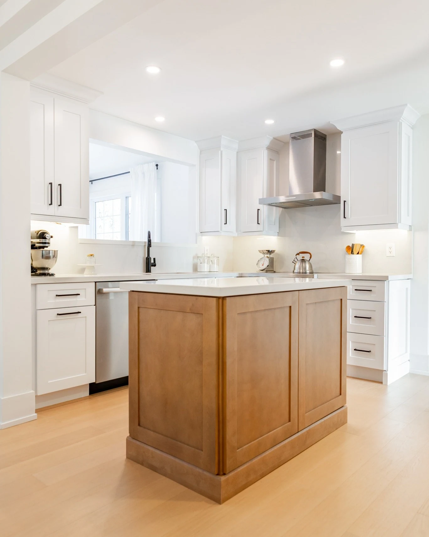 White kitchen with wood-panelled island and hanging pendant lights