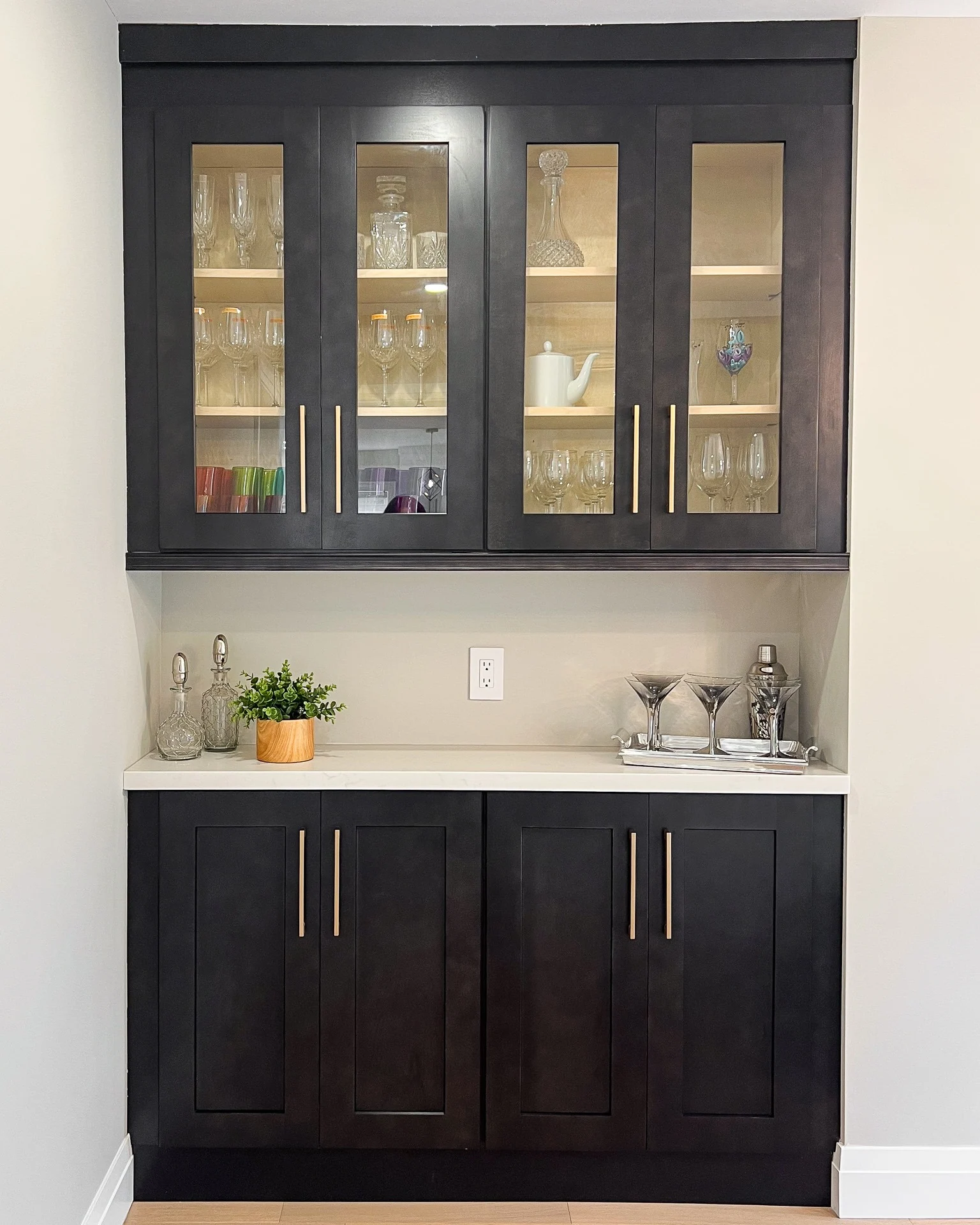 Glass-front display cabinetry with warm lighting and dark base